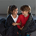 Two kids wrapped up in a weighted blanket