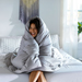Woman wrapped up in a gray comforter