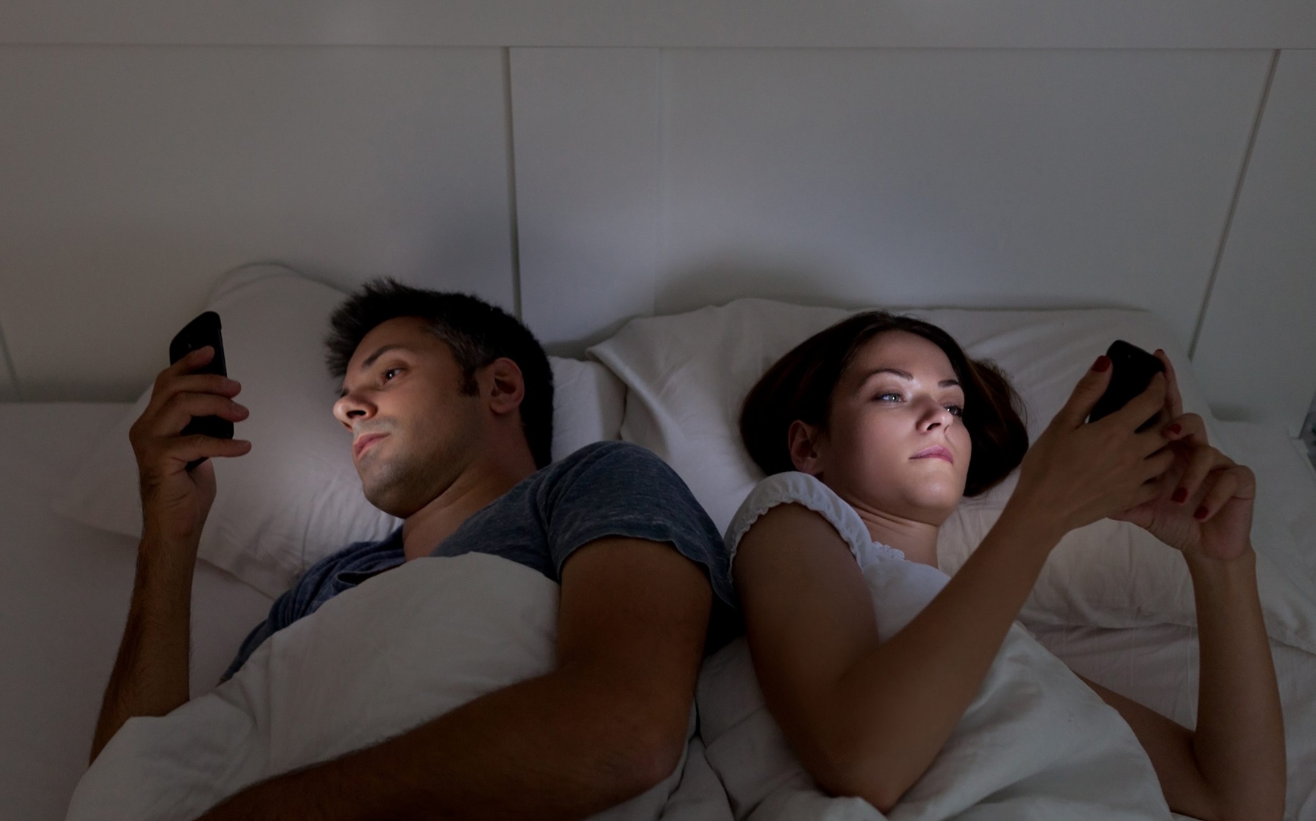 Couple watching phone on bed